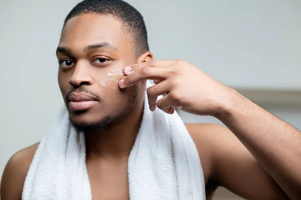 Homme africain soins de la peau homme appliquant crème visage — Photo