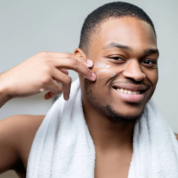 Man gezichtsverzorging afrikaanse man aanbrengen gezichtscrème — Stockfoto