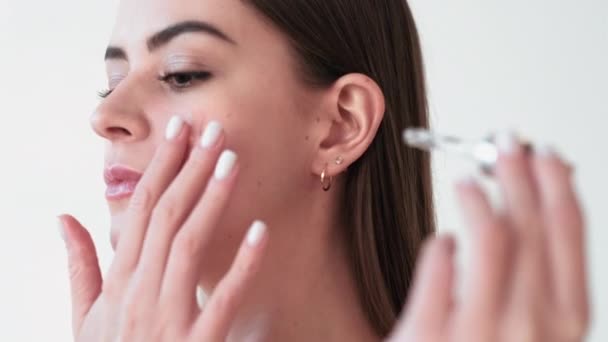 Женщина с кожей лица наносит сыворотку масла на лицо — стоковое видео