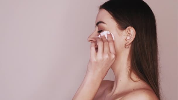 Догляд за шкірою жінка очищає обличчя бавовняною подушечкою — стокове відео