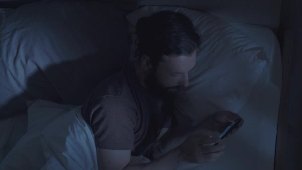 Internet podvod noc muž pomocí telefonu v posteli — Stock video