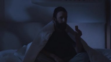 Uykusuz gece yorgun adam sıkıcı bir TV programı izliyor.