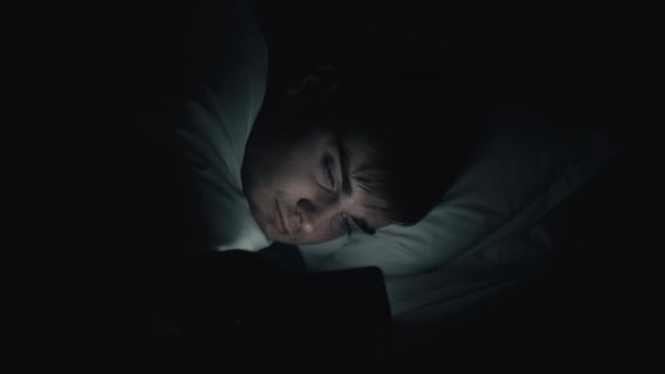 Gece sohbeti internet yorgunluğu yatakta yorgun adam telefonu — Stok video