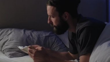 Gece evde kitap okuyarak, yatakta boş adam okuyarak.