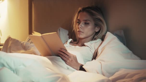 Cama leitura noite fadiga sonolenta mulher com livro — Vídeo de Stock
