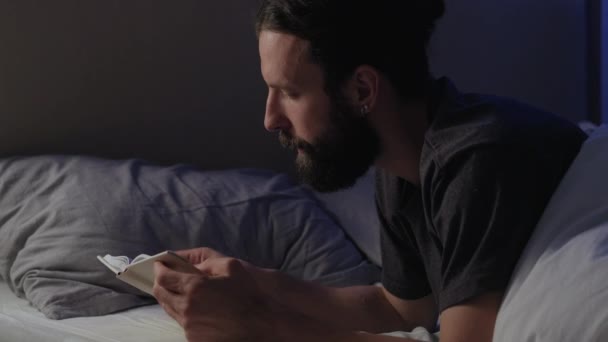 Noc czytanie w domu wypoczynek człowiek w łóżku z książki — Wideo stockowe