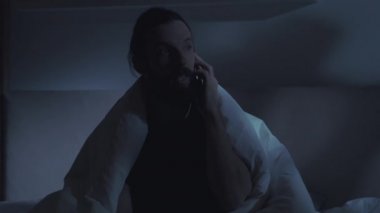 Yatakta cep telefonlu iletişimci adam telefonu