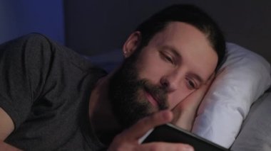 Mobil gece yatağı alışkanlığı olan adam telefonda film izliyor.