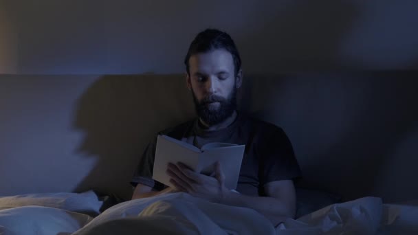 Cama lectura noche fatiga somnoliento hombre cierre libro — Vídeos de Stock