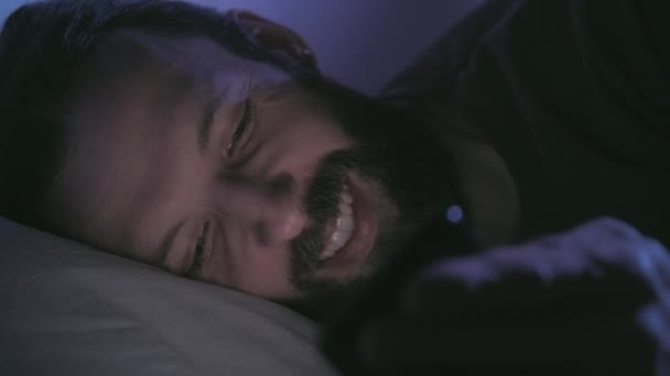 Gadget noche tarde chat feliz hombre en la cama con teléfono — Vídeo de stock