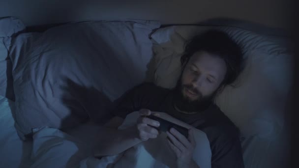 Nacht film man kijken leuke video op telefoon in bed — Stockvideo