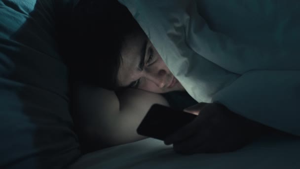 夜オンライン不眠症の男の電話ベッドで — ストック動画