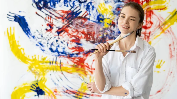 Mulher pintura divertido com paintbrushes parede colorida — Fotografia de Stock
