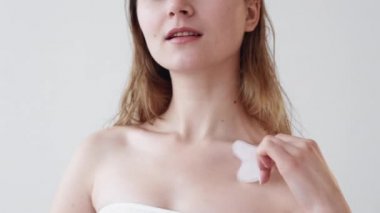 Gua sha cilt masajı aletine dokunan kadın.