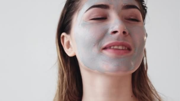 Домашняя красотка с голубой глиняной маской на лице — стоковое видео