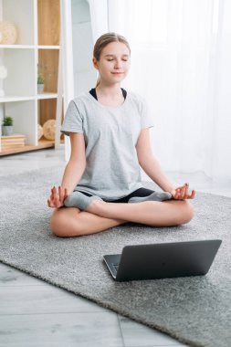 Çocuklar evde yoga yapıyor. Bilgisayarlı meditasyon kızı.
