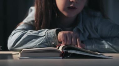 Gece geç saatte evde eğitim gören kız kitap okuyor.