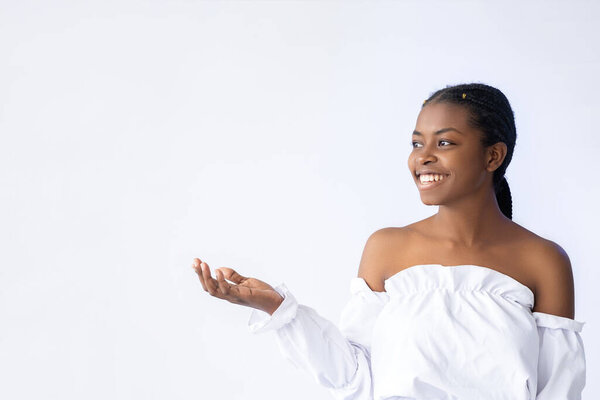 Pointing woman. Discount offer. Promotional background. Great opportunity. Happy smiling African lady presenting invisible empty space product isolated on white.