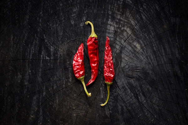 Některé horké červené papriky leží na tmavé desce — Stock fotografie