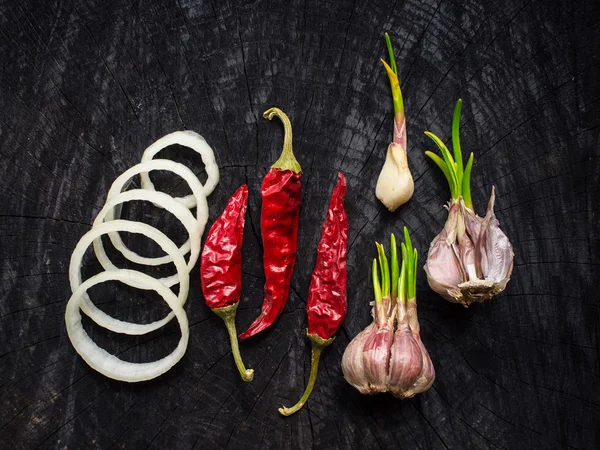 Lök, röd paprika och vitlök på ett mörkt bord — Stockfoto