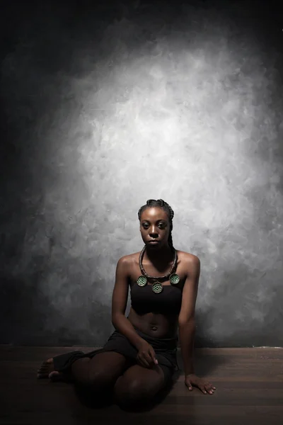 La bella donna nera si siede su un piano — Foto Stock