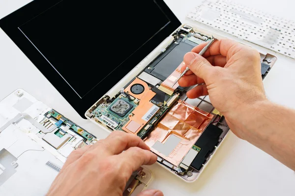 O engenheiro repara o laptop (pc, computador) e a motherboa — Fotografia de Stock