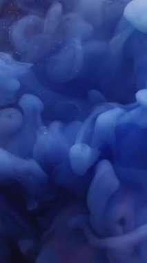 Dikey video. Su dumanı. Soyut mürekkep dalgası. Odaklanmamış mavi pembe renk boya sıvı ruhani su sanat arka planında akıyor..