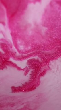 Dikey video. Parıltı akıyor. Parlak bir geçmişi var. Odaklanmamış pembe renkli su boyası soyut mermer emaye sanatı üzerine dökülen sıvı dalga..