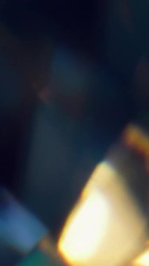 Dikey video. Hafif doku. Bulanık işaret fişeği sızıntısı. Soyut koyu siyah arkaplan üzerinde odaksız sarı mavi yanıp sönen renkli renkli optik gökkuşağı.