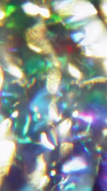 Dikey video. Işık yansıması. Bulanık kristal gökkuşağı. Odaklanmamış yeşil mor renkli spektrum mercek soyut arkaplanda yanıp sönüyor.