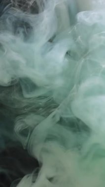 Dikey video. Boya damlası suyu. Duman bulutu. Odaklanmamış mavi renkli buhar dokusu mürekkep sıçratma damlası soyut sis sanatının arka planında.