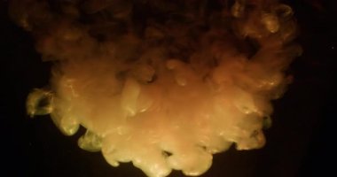 Duman bulutu. Mürekkep arkaplanı. Odaklanmamış turuncu renkli parıltılı su sisli gökkuşağı parçacıkları akrilik sanata yayılıyor koyu siyah soyutlama.