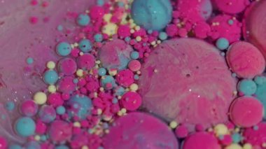 Boya maddesi. Renk sıvısı. Odaklanmamış pembe, sarı, parlak mürekkep damlaları soyut arka planda süzülen parlak pigmentler..