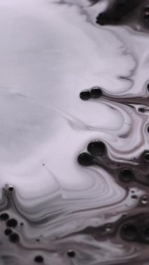 Dikey video. Yağ sanatı. Boya karışımı. Odaklanmamış beyaz süt rengi mürekkep köpüğü su kabarcığı sıvı damlaları soyut sanat eserine dökülüyor koyu siyah arkaplan.