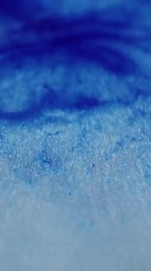 Dikey video. Mermer dokusu. Odaklanmamış sim sanatı. Yanıp sönen mavi renkli sıvı akışı bulanık bokeh hafif modern arkaplanda hareket ediyor.