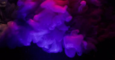 Mürekkep sıçraması. Neon parlak parçacıklar. Odaklanmamış mor pembe parlak gökkuşağı bulutu soyut karanlık sanat arka planında yayılıyor..