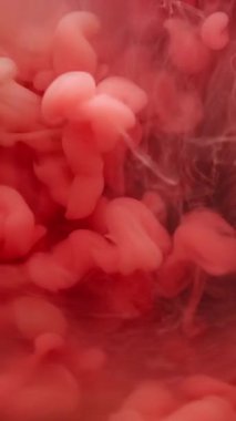 Dikey video. Renk akışı. Buhar arka planı. Odaklanmamış pembe bulut dokusu duman sıçratıyor. Soyut sanat eserleri üzerinde yüzen suya duman karışımı boya sıçrıyor..