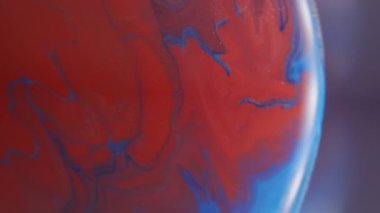 Akrilik yayılmış. Bulanık boya karışımı. Dairesel ışık lensinde kırmızı mavi emülsiyon karışımı. Odaklanamayan renk arkaplanı üzerindeki girdap akışı.