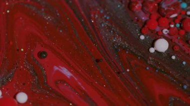 Boya sıçraması. Renk sıvısı. Odaklanmamış kırmızı mor parlak mürekkep damlacıkları soyut arkaplanda parıldayan parlak pigmentler..