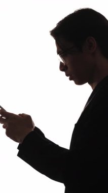 Dikey video. İş yardımı. Profesyonel işbirliği. Çevrimiçi çalışan çeşitli takımların karanlık profil silueti beyaz üzerinde izole edilmiş telefon kullanıyor.