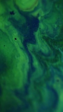 Dikey video. Shimmer düşüyor. Odaklanmamış sim karışımı. Yeşil mavi, parlak renkli boya sıvısı soyut, aydınlık, modern arka planda bulanıklaşıyor..