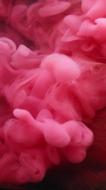Dikey video. Su altı patlaması. Boya suyu sıçraması. Soyut sanat arka planında pembeleşmiş kırmızı duman dokusu akışı.