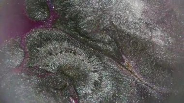 Mürekkep sıçraması. Parlak akıntı. Odaklanmamış mor gümüş rengi parlak doku soyut koyu siyah arkaplan üzerine yayılan parçacık akışı.