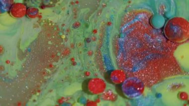 Canlı bir sıvı. Renk sıvısı. Odaklanmamış yeşil mavi parlak mürekkep köpükleri soyut arkaplanda parlayan turuncu pigmentler..