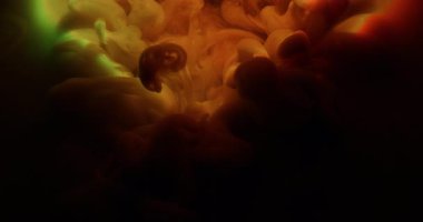 Mürekkep sıçraması. Parlak parçacıklar. Odaklanmamış turuncu yeşil renkli parlak gökkuşağı bulutu soyut koyu siyah arka planda yayılıyor..