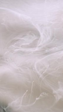 Dikey video. Sıçrama dokusu. Soyut boya suyu. Soyut arkaplanda dönen sıvı akışkan sıvıda odaksız beyaz süt rengi mürekkebi.