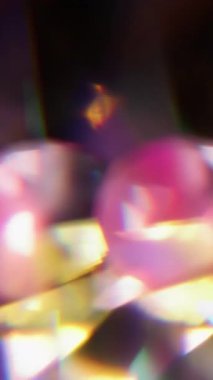 Dikey video. Işıl ışıl. Bulanık parlak doku. Odaklanamayan pembe floresan aydınlık cam geometrik lens soyut koyu siyah arkaplanda yanıp sönüyor..