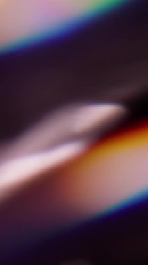 Dikey video. Işık huzmesi. Görüntü pırıltısı. Odaklanamayan mavi yeşil çok renkli lens, ışık tayfı koyu siyah sanat arka planında parıldıyor..