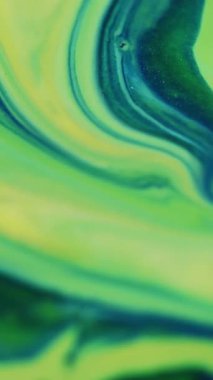 Dikey video. Yeşil boya karışımı. Odaklanmış parçacık sıvısı. Bulanık modern sanat ışığı arka planında sarı yeşil renkli sıvı akış kimyasal dokusu.