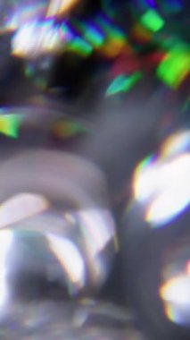 Dikey video. Kaleydoskop titreşiyor. Bulanık ışık. Odaklanamayan yeşil turuncu mercek soyut sanatın koyu arkaplan üzerindeki ışık çemberlerini yansıtıyor..